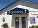Charming clubhouse entrance with palm tree accents and pool rules posted on white exterior at 3710 Gulf Of Mexico Dr # D19, Longboat Key, FL 34228