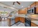 Open kitchen with stainless steel appliances and wood cabinets, overlooking the living room at 5384 Sarapointe Ct, Sarasota, FL 34232