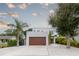 White two-story house with wood garage door and landscaping at 5906 Larchwood Ave, Sarasota, FL 34231