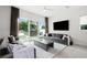 Spacious living room with gray sofas, a large TV, and sliding doors leading to a backyard patio at 5906 Larchwood Ave, Sarasota, FL 34231