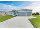 Newly built home with light blue exterior, three-car garage and large driveway at 75 Mark Twain Ln, Rotonda West, FL 33947