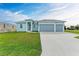 Newly built home with light blue exterior, three car garage and spacious lawn at 75 Mark Twain Ln, Rotonda West, FL 33947