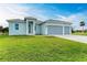 Two story home with light blue exterior, three car garage and landscaped yard at 75 Mark Twain Ln, Rotonda West, FL 33947