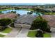 Three-car garage villa with dark brown tile roof, next to a lake at 8199 Varenna Dr, Sarasota, FL 34231