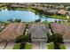 Three-car garage villa with dark brown tile roof, next to a lake at 8199 Varenna Dr, Sarasota, FL 34231