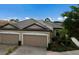 Three-car garage villa with dark brown tile roof, next to a lake at 8199 Varenna Dr, Sarasota, FL 34231