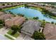 Three-car garage villa with dark brown tile roof, next to a lake at 8199 Varenna Dr, Sarasota, FL 34231