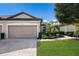 Tan three-car garage villa with paved driveway, landscaping, and walkway at 8199 Varenna Dr, Sarasota, FL 34231