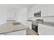 Modern kitchen with white cabinets, granite countertops, and stainless steel appliances at 10611 Ladybug Cv, Parrish, FL 34219