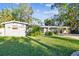Ranch-style home with lush green lawn and mature trees at 1100 27Th W Ave, Palmetto, FL 34221
