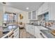 White kitchen with granite countertops and beach-themed backsplash at 1211 Gulf Of Mexico Dr # 403, Longboat Key, FL 34228