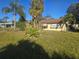 House with palm trees and overgrown grass at 1346 Kenmore St, Port Charlotte, FL 33952