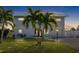 Two-story house with metal roof, palm trees, and well-lit front yard at dusk at 1790 Ezelle Ave, Largo, FL 33770