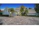 Two-story house with gray brick exterior, palm trees, and a paver driveway at 4892 Peregrine E Pt, Sarasota, FL 34231
