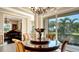 Elegant dining room with glass-top table, chandelier, and view of backyard at 6337 Rivo Lakes Blvd, Sarasota, FL 34241