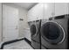 Laundry room with gray washer and dryer, white cabinets, and a patterned rug at 1021 Fernleaf Run, Bradenton, FL 34212