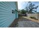 Side yard with gravel, wooden fence, and mature trees at 1213 5Th W St, Palmetto, FL 34221