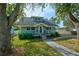 Charming light teal house with a grey roof, front porch, and landscaped yard at 1213 5Th W St, Palmetto, FL 34221