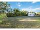 Spacious, grassy backyard featuring mature trees, foliage, and a storage shed at 21907 Cellini Ave, Port Charlotte, FL 33952