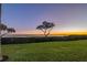 Sunset view from backyard with grassy lawn, hedges, and water at 61 Tidy Island Blvd, Bradenton, FL 34210
