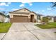 One-story house with brown garage door, gray door, and landscaped yard at 7308 Tangle Bend Dr, Gibsonton, FL 33534