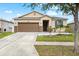 One-story house with brown garage door, gray door, and landscaped yard at 7308 Tangle Bend Dr, Gibsonton, FL 33534