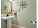 Elegant powder room with pedestal sink, decorative mirror, and tasteful wall art at 348 165Th Ne Ct, Bradenton, FL 34212