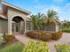 Front entry with arched doorway, brick walkway, and lush landscaping at 4472 Via Del Villetti Dr, Venice, FL 34293