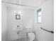 Small bathroom with white tile, toilet, sink, and grab bar at 5645 Churchill Downs Rd, Sarasota, FL 34241