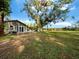 House exterior with large oak tree and pond view at 5645 Churchill Downs Rd, Sarasota, FL 34241