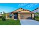 House exterior showcasing a stone accent, landscaping, and a modern garage door at 6138 162Nd E Ave, Parrish, FL 34219