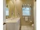 Small bathroom with white vanity and striped wallpaper at 770 Egret Walk Ln, Venice, FL 34292