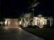 Well-lit house exterior at night, featuring a large driveway and lush landscaping at 770 Egret Walk Ln, Venice, FL 34292