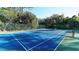 Blue tennis court surrounded by trees at 770 Egret Walk Ln, Venice, FL 34292