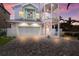 Pastel-colored three-story house with a two-car garage and brick driveway at 112 Mangrove Ave, Anna Maria, FL 34216