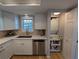 White kitchen with stainless steel appliances and stacked washer/dryer at 1552 Stickney Point Rd # 403, Sarasota, FL 34231
