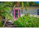 Inviting home entrance with a vibrant pink door and lush landscaping at 1740 Maryknoll Rd, Englewood, FL 34223