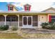 Front porch with red door, white railings and landscaping at 27425 Jones Loop Rd, Punta Gorda, FL 33982