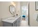 Clean bathroom with octagonal mirror, gray vanity and a view of bedroom at 3015 Avenue E, Holmes Beach, FL 34217
