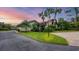 Beautifully landscaped home with a lush green lawn, mature palm trees, and a winding driveway at 3102 Windrush Bourne # 4, Sarasota, FL 34235