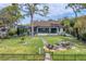 House back view with a large grassy yard, fire pit, and a dock at 603 Harbor Shore Dr, Nokomis, FL 34275