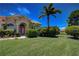 Landscaped yard with lush greenery and palm trees, showcasing a beige house at 644 Rivendell Blvd, Osprey, FL 34229