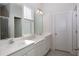Double vanity bathroom with white cabinets and large mirrors at 9814 Daybreak Gln, Parrish, FL 34219