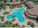 Aerial view of a luxurious pool area with ample seating, umbrellas and lush landscaping at 12651 Garibaldi Ln, Venice, FL 34293