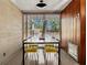 Dining room with a modern table, yellow chairs, wood-paneled walls, and bright light from the window at 1695 Lowe Dr, Sarasota, FL 34236