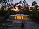 A contemporary home with a light exterior at dusk surrounded by mature trees at 1695 Lowe Dr, Sarasota, FL 34236