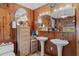 Vintage bathroom with double sinks, wood paneling, and a view of the backyard at 39200 Cook Brown Rd, Punta Gorda, FL 33982