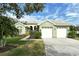 Light green house with two-car garage, landscaping, and a paved driveway at 5097 Faberge Pl, Sarasota, FL 34233