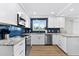 Modern kitchen with white cabinets, blue tile backsplash, and granite countertops at 6326 Midnight Pass Rd # 101, Sarasota, FL 34242