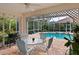 Covered patio with outdoor dining set and grill, next to the pool area at 7207 Saint Johns Way, University Park, FL 34201